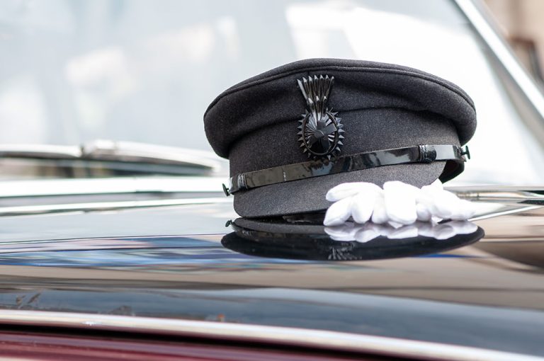 Chauffeur's hat sitting on the hood of a limo