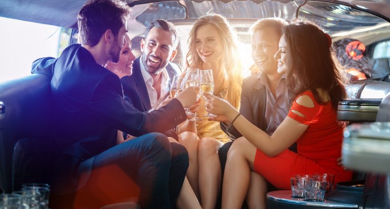 Group of friends having a night out in a limo with glasses of champagne