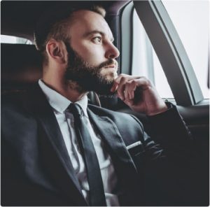 Businessman in suit sitting in car looking out window thoughtfully