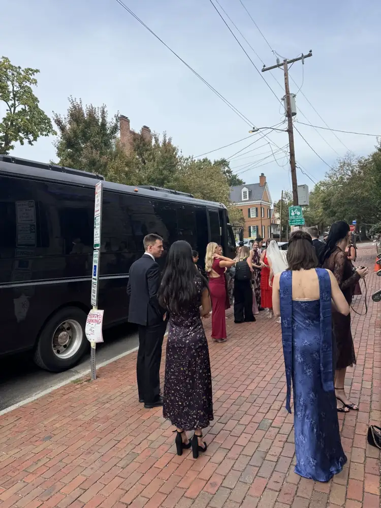 Wedding guests gathering to board an RDV Limousine party bus on a brick sidewalk in Old Town Alexandria